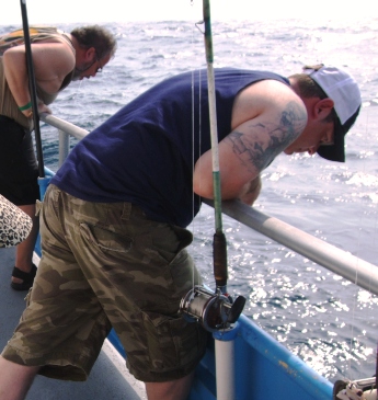 Men hang over the railing as seasickness takes hold